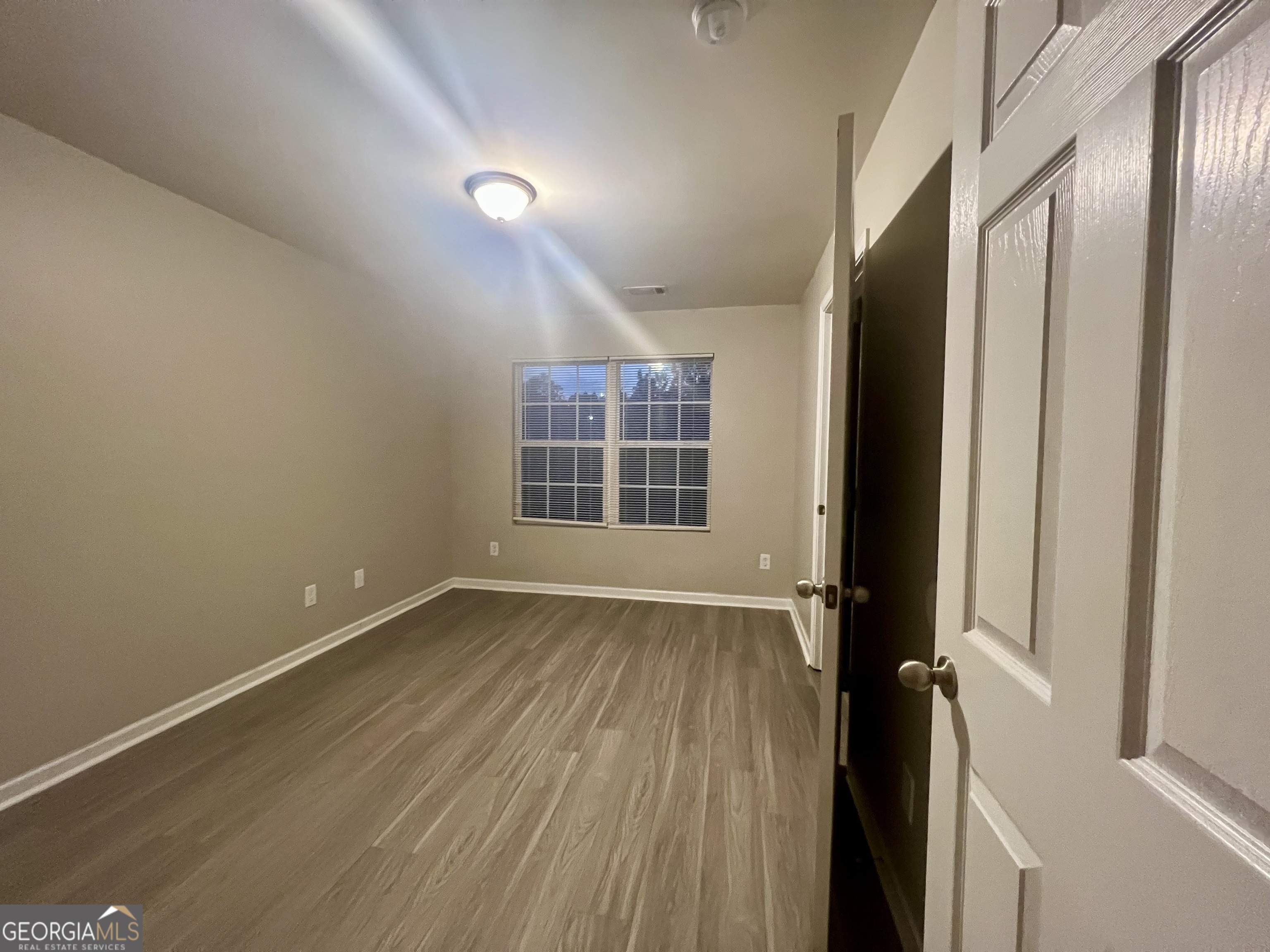 1005 Mill Creek Way, Unit B Monroe, GA 30655 - Photo 6 of 11 an empty room with wooden floor and windows