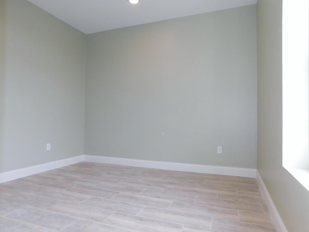 10 Roxbury Street, Unit 8 Boston, MA 02119 - Photo 8 of 10 a view of an empty room with wooden floor and a window