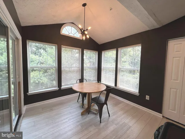 a dining room with wooden floor a chandelier a wooden table and chairs