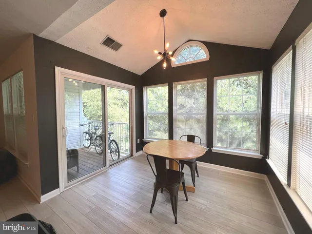 a dining room with wooden floor a chandelier a wooden table and chairs