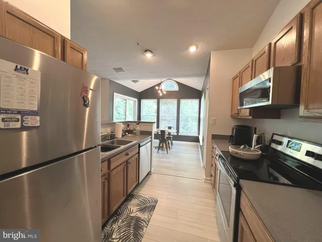 a kitchen with stainless steel appliances granite countertop a refrigerator a stove a sink dishwasher a oven with white cabinets and wooden floor