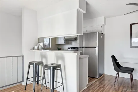 a kitchen with stainless steel appliances a refrigerator a stove a dining table and chairs with wooden floor