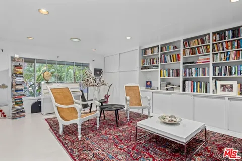 a work room with furniture bookshelf and a large window