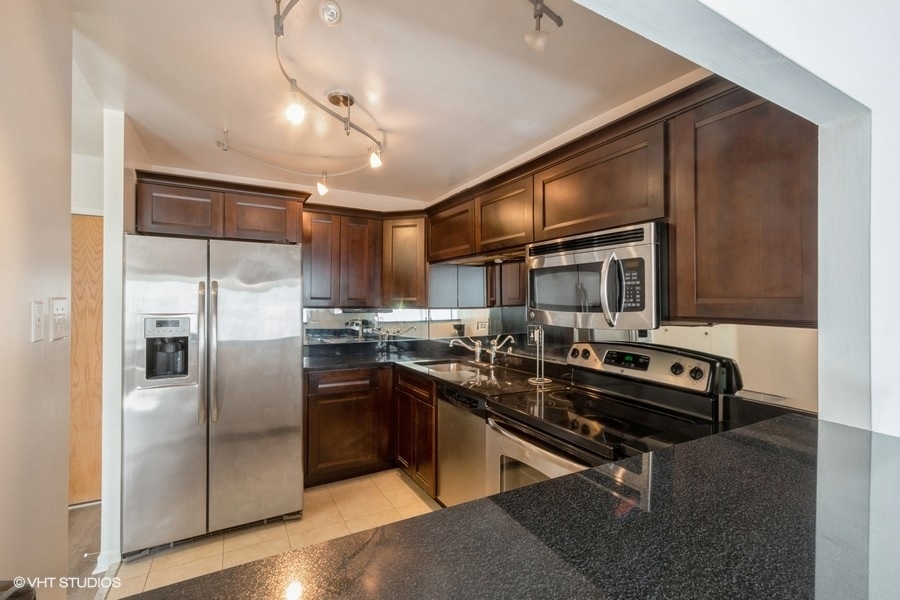 211 East Ohio Street, Unit 2012 Chicago, IL 60611 - Photo 5 of 19 a kitchen with stainless steel appliances kitchen island granite countertop a refrigerator a stove and a sink with wooden floor