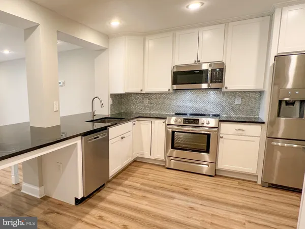 a kitchen with stainless steel appliances granite countertop a stove a sink and a refrigerator