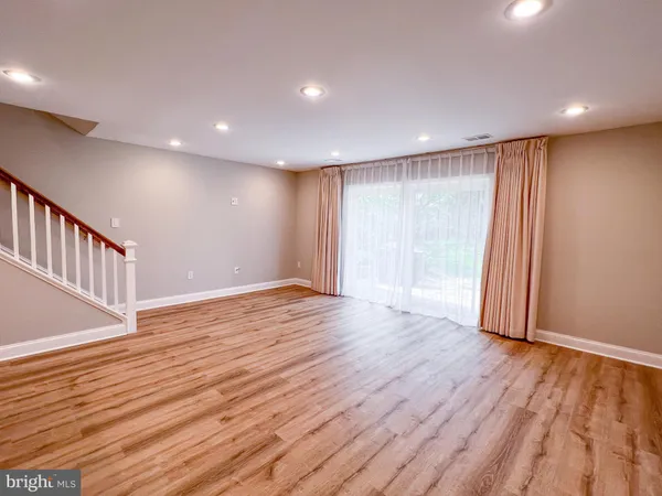 a view of an empty room with wooden floor and staircase