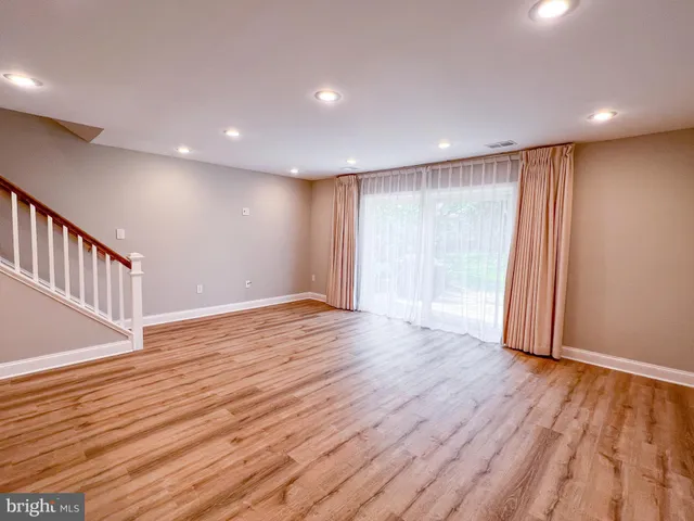 a view of an empty room with wooden floor and staircase