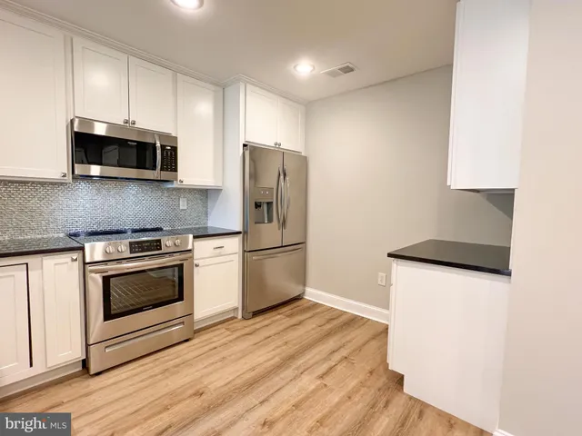 a kitchen with stainless steel appliances a stove a microwave and a hard wood floors