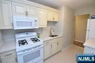 a kitchen with white cabinets and appliances