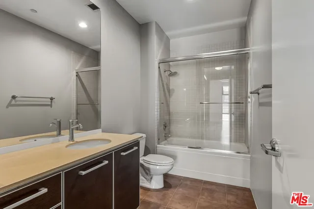 a bathroom with a double vanity sink toilet mirror and shower