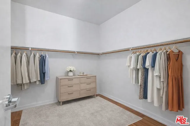 a view of walk in closet with clothes and shoes