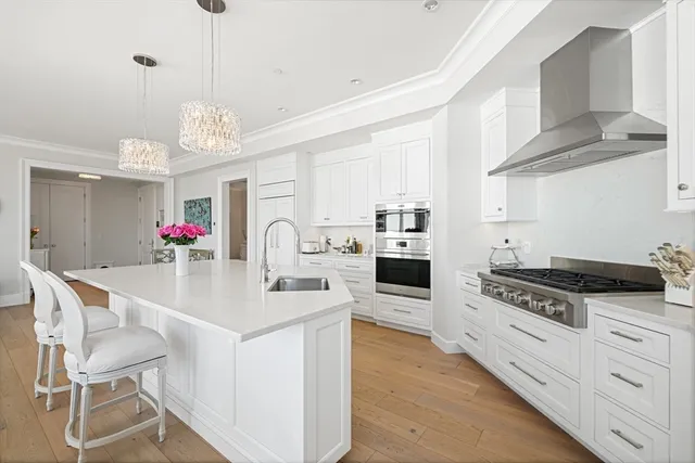 a kitchen with stainless steel appliances granite countertop a sink dishwasher and white cabinets with wooden floor