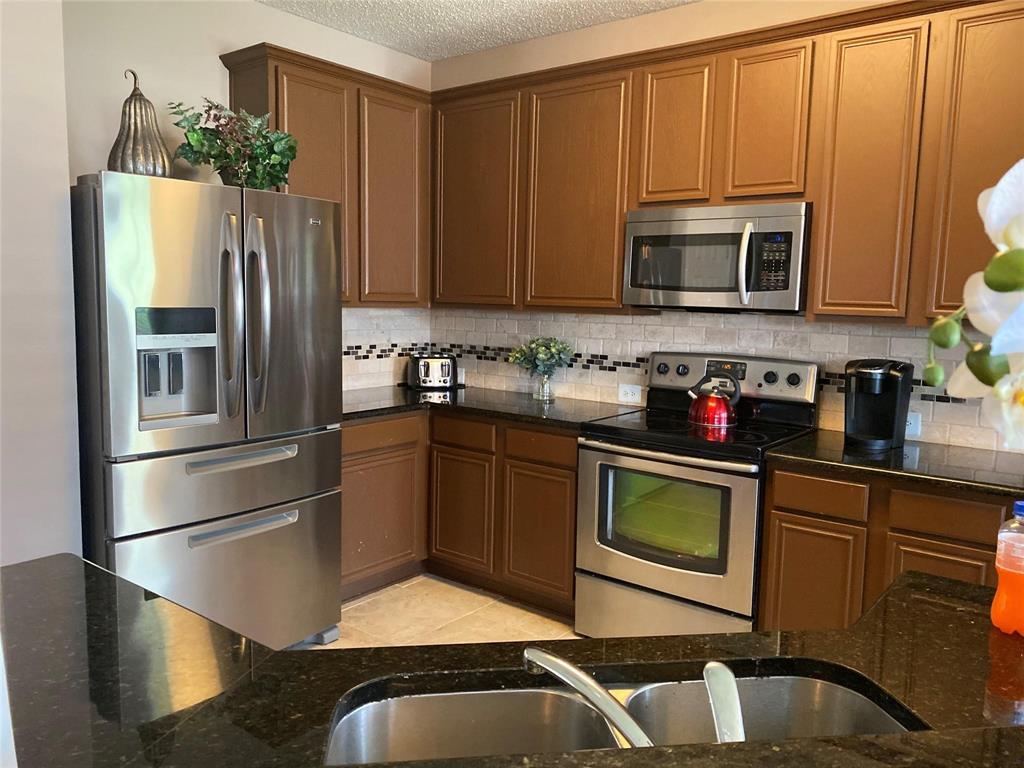 4025 Steepleridge Drive The Colony, TX 75056 - Photo 6 of 23 a kitchen with stainless steel appliances granite countertop a refrigerator a stove a sink and a microwave