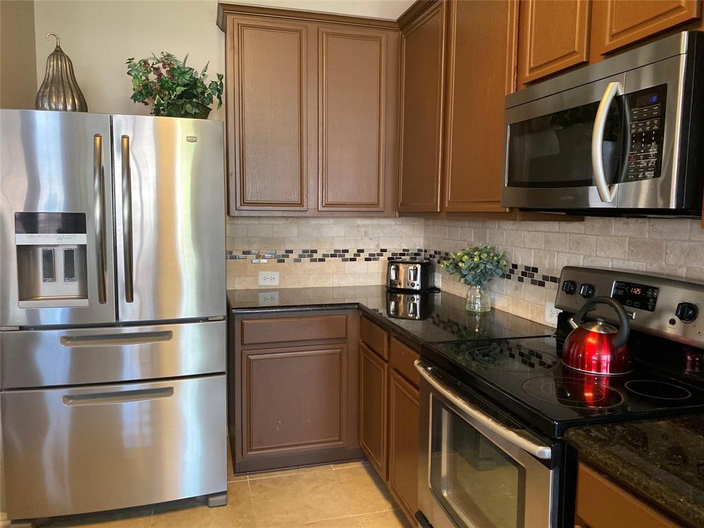4025 Steepleridge Drive The Colony, TX 75056 - Photo 8 of 23 a kitchen with stainless steel appliances granite countertop a refrigerator stove and microwave