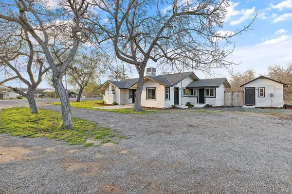 a view of a house with a yard and large tree