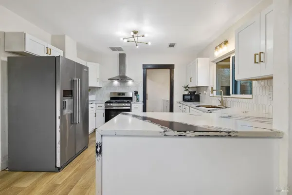 a living room with stainless steel appliances kitchen island granite countertop a refrigerator and a stove top oven