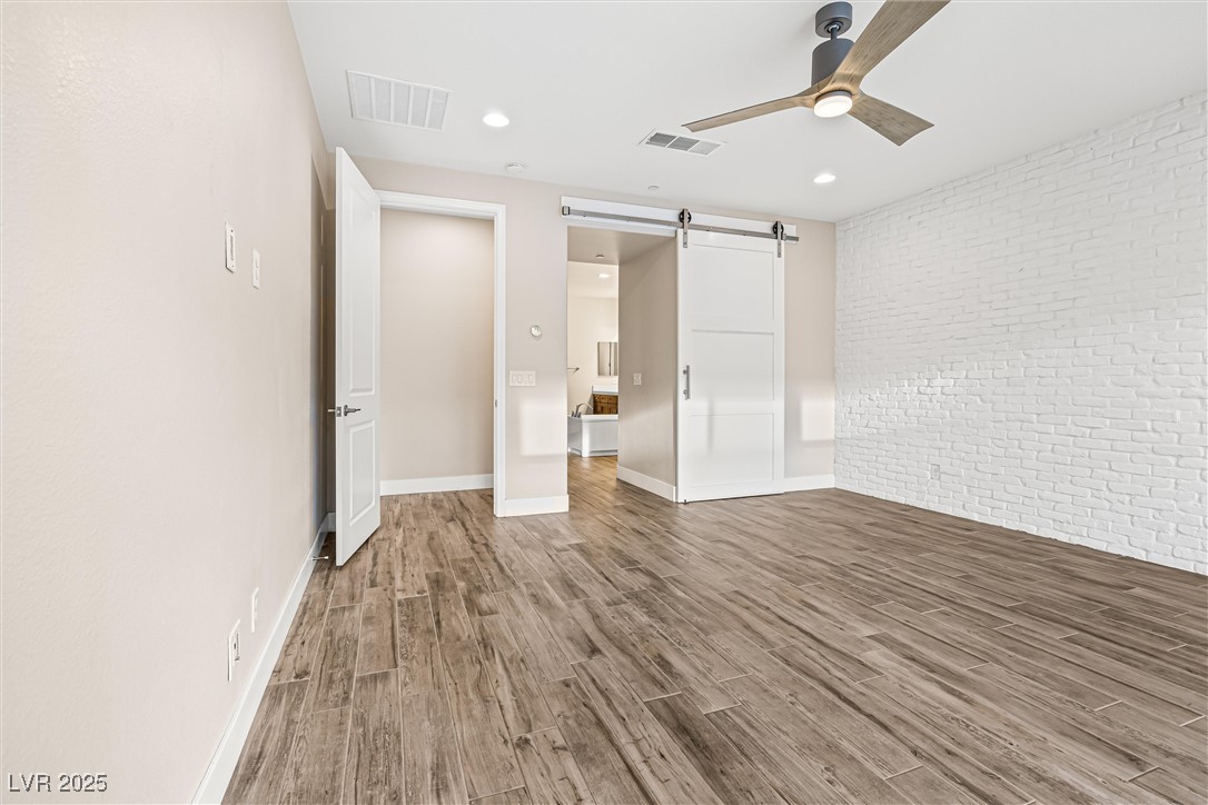 4631 Amazing View Street Las Vegas, NV 89129 - Photo 27 of 94 Unfurnished bedroom with brick wall, a barn door, wood finished floors, a ceiling fan, and recessed lighting