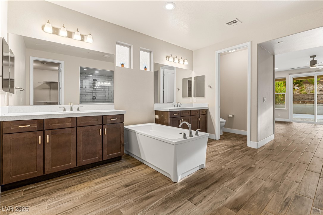 4631 Amazing View Street Las Vegas, NV 89129 - Photo 30 of 94 Bathroom featuring two vanities, light wood-style floors, a shower stall, ceiling fan, and a walk in closet