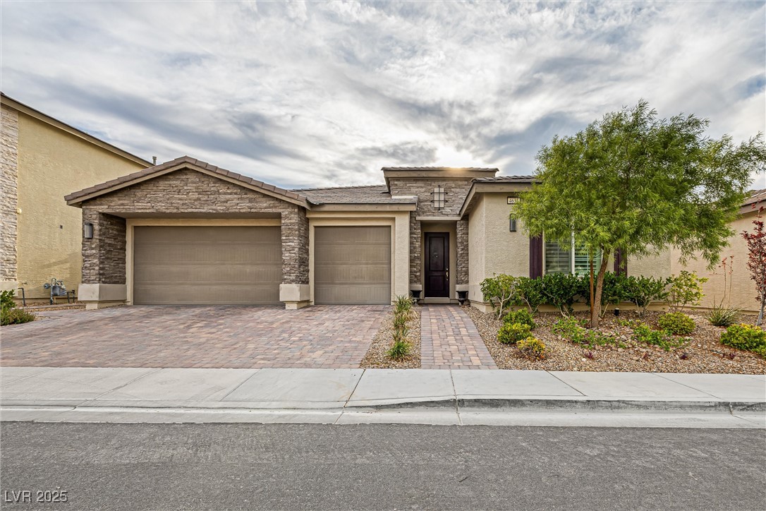 4631 Amazing View Street Las Vegas, NV 89129 - Photo 9 of 94 View of front facade with stone siding, stucco siding, decorative driveway, and an attached garage