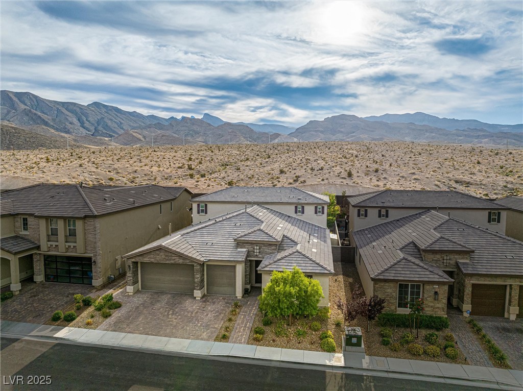 4631 Amazing View Street Las Vegas, NV 89129 - Photo 91 of 94 View of front facade featuring stone siding, a garage, a mountain view, decorative driveway, and stucco siding