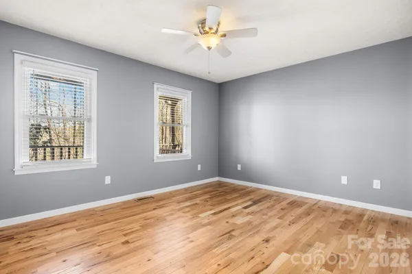 a view of an empty room with window and wooden floor