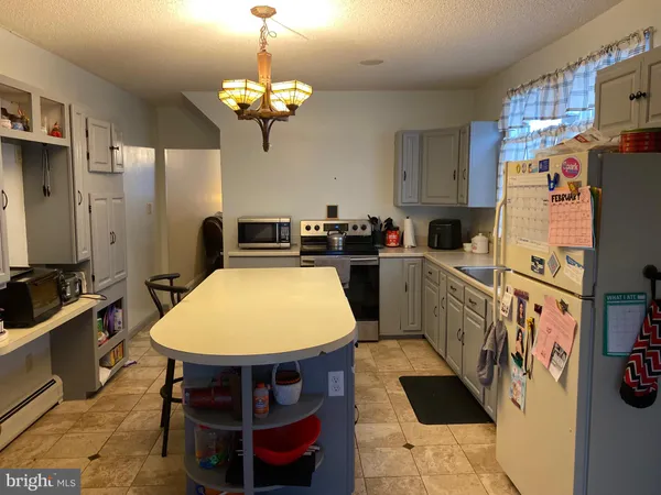 a kitchen with stainless steel appliances a stove a refrigerator a sink a dining table and chairs with wooden floor