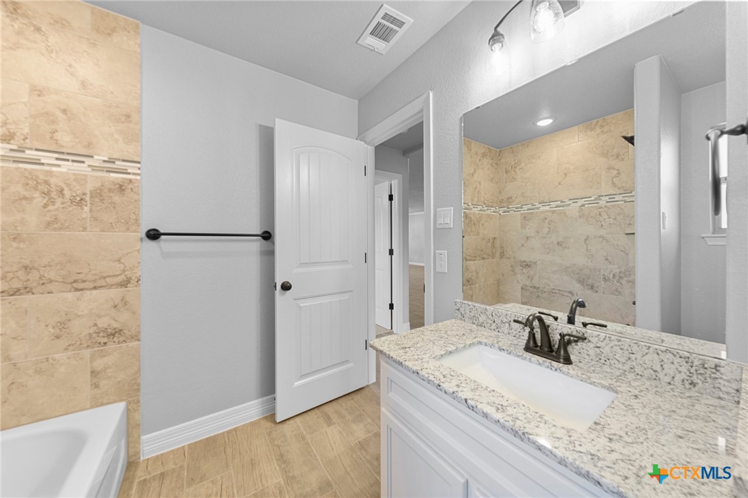 3030 Millhouse Road Copperas Cove, TX 76522 - Photo 9 of 24 a bathroom with a granite countertop sink mirror and a bathtub