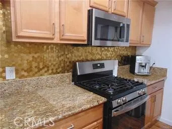 a kitchen with granite countertop a stove and a white cabinets