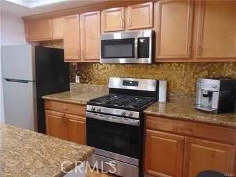 a kitchen with stainless steel appliances granite countertop a stove microwave refrigerator and sink