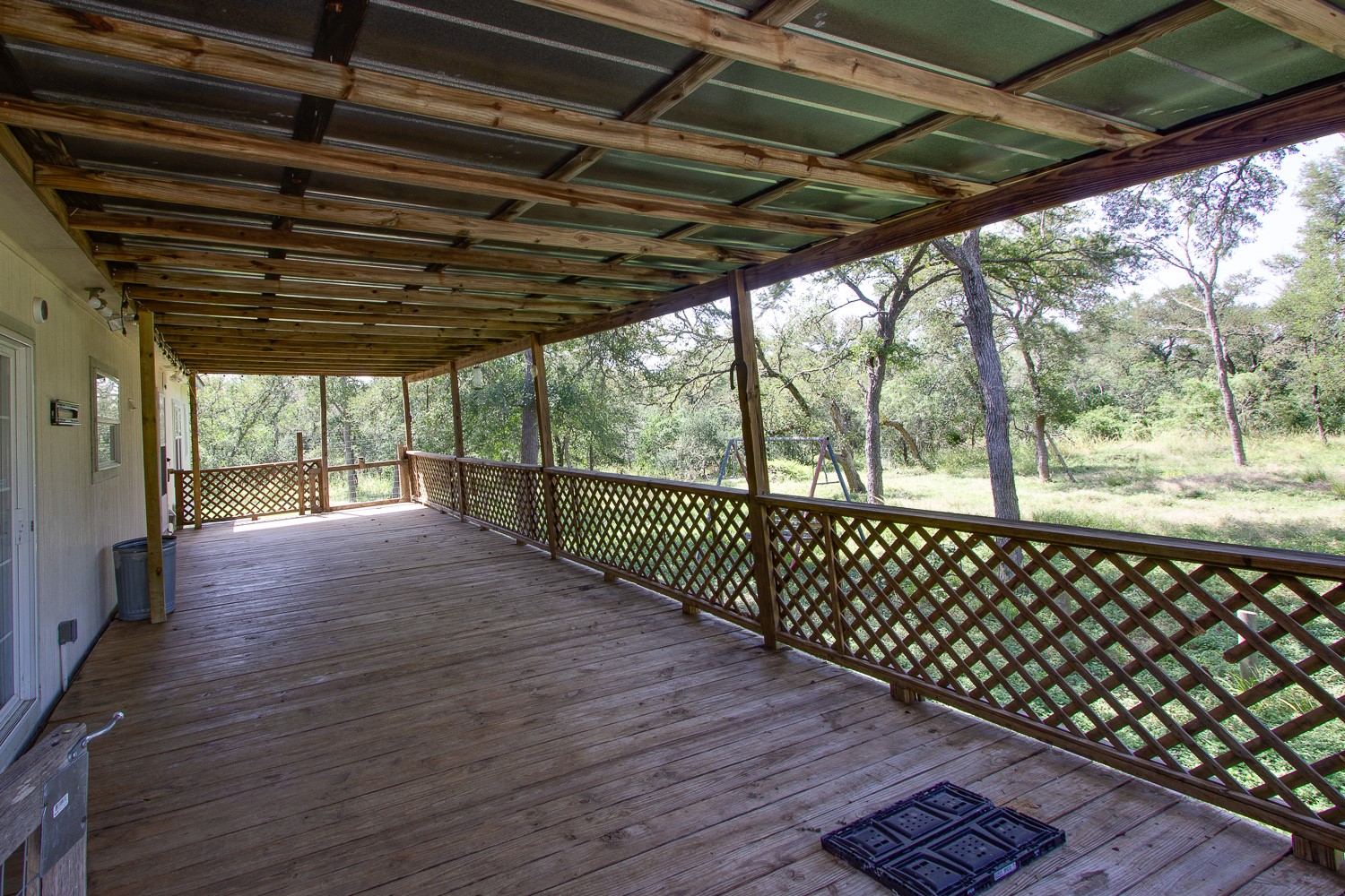 133 Mark Adams Road Del Valle, TX 78617 - Photo 18 of 20 An expansive covered wooden deck looks out over a tranquil, tree-lined backyard setting.