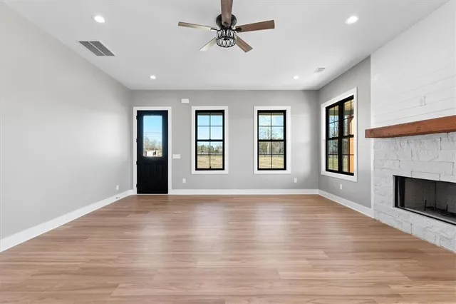 an empty room with windows and fireplace