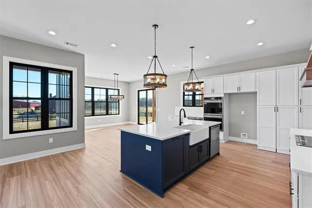 a kitchen with kitchen island granite countertop wooden floors and white cabinets
