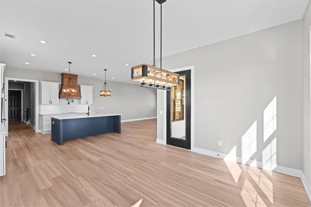 a view of a kitchen with kitchen island a sink wooden floor and a chandelier