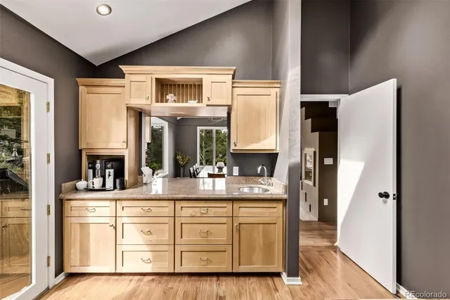 a kitchen with stainless steel appliances granite countertop a refrigerator a sink dishwasher a stove and a dining table with wooden floor