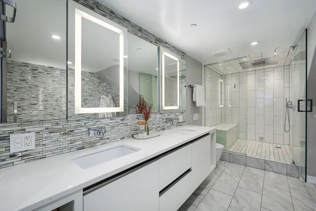 a bathroom with a double vanity sink mirror and shower