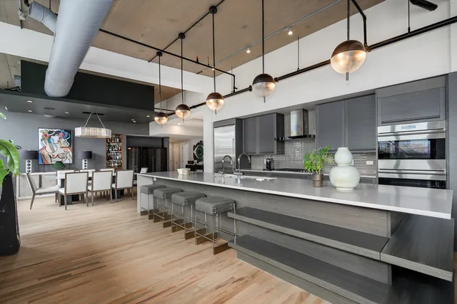 a kitchen with stainless steel appliances kitchen island granite countertop a stove a sink and a wooden floors