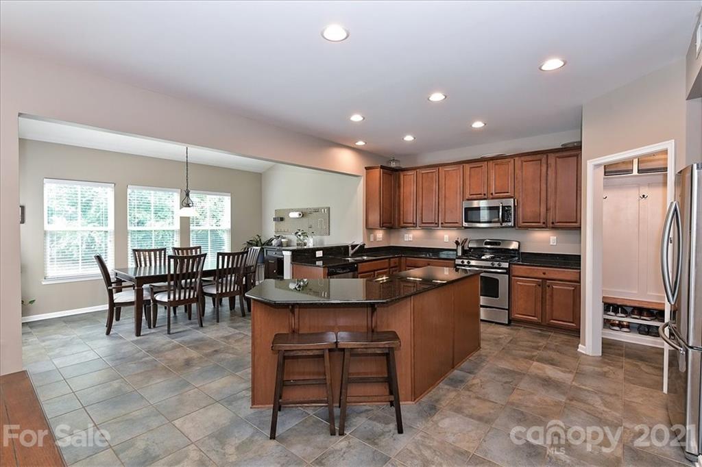 3007 Fallondale Road Waxhaw, NC 28173 - Photo 11 of 46 a kitchen with kitchen island granite countertop wooden cabinets dining table and stainless steel appliances
