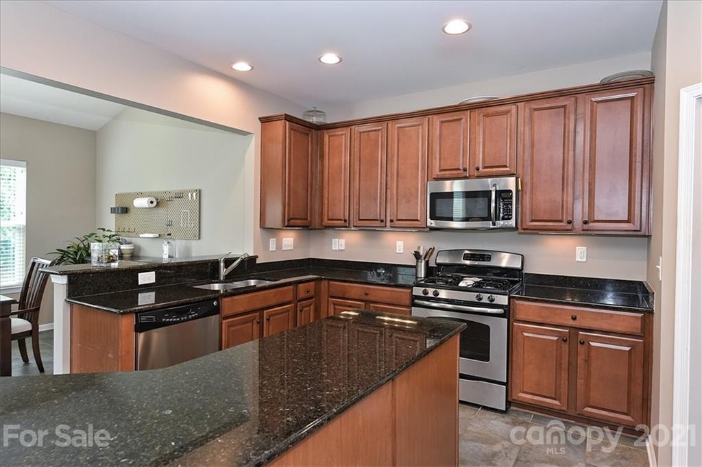 3007 Fallondale Road Waxhaw, NC 28173 - Photo 12 of 46 a kitchen with kitchen island granite countertop a sink a stove top oven a counter space and cabinets