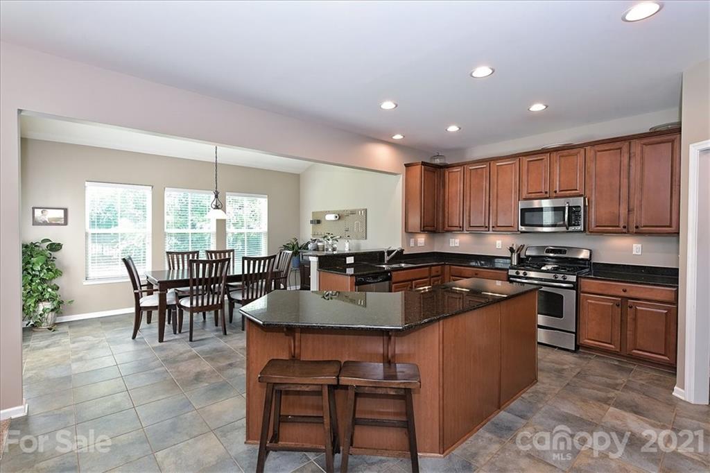 3007 Fallondale Road Waxhaw, NC 28173 - Photo 13 of 46 a kitchen with stainless steel appliances granite countertop table chairs sink and stove top oven