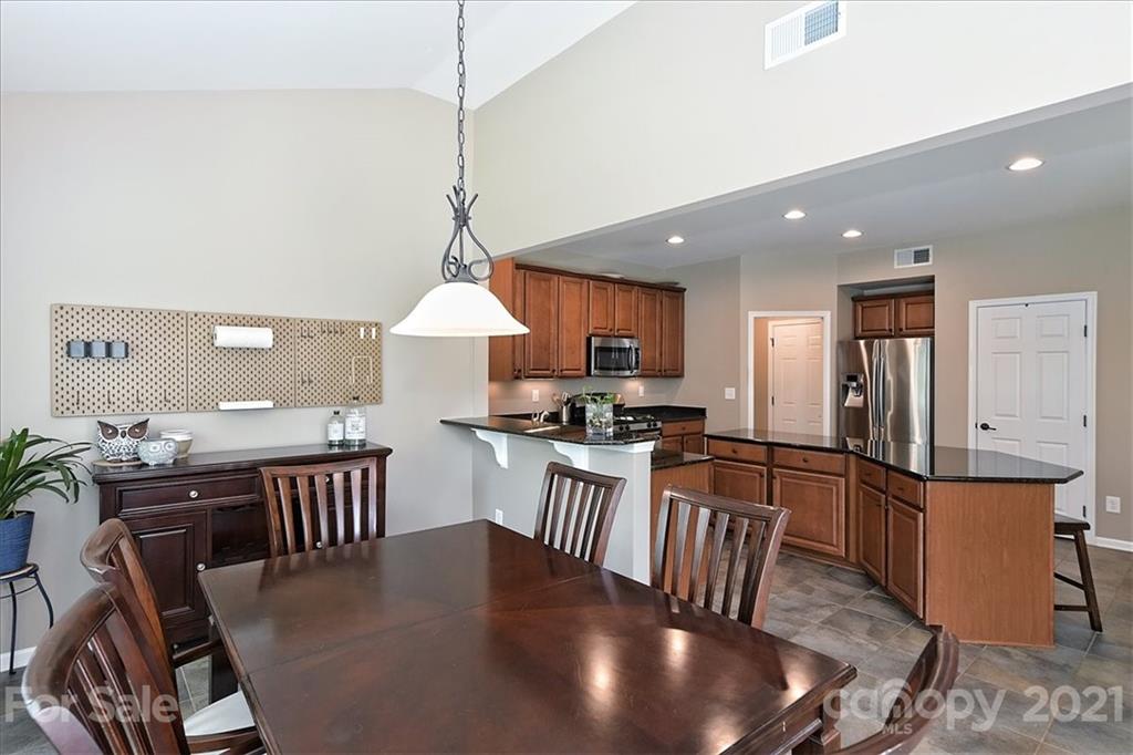 3007 Fallondale Road Waxhaw, NC 28173 - Photo 16 of 46 a kitchen with stainless steel appliances granite countertop a stove a refrigerator a kitchen island a dining table and chairs with wooden floor