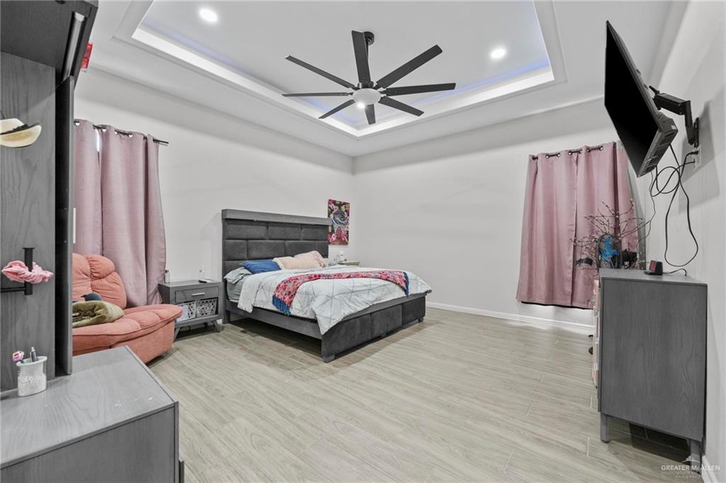 23247 Uresti Road Edinburg, TX 78542 - Photo 6 of 18 Tray ceiling with recessed lighting and a ceiling fan, light wood-finish flooring, and white walls