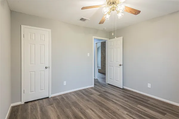 wooden floor in an empty room with a chandelier fan