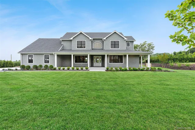 a front view of a house with a garden and trees