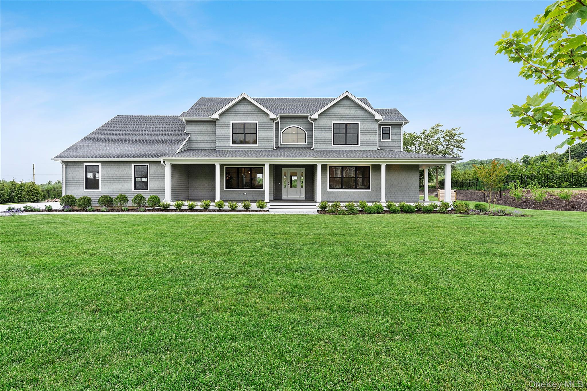 a front view of a house with a garden and trees