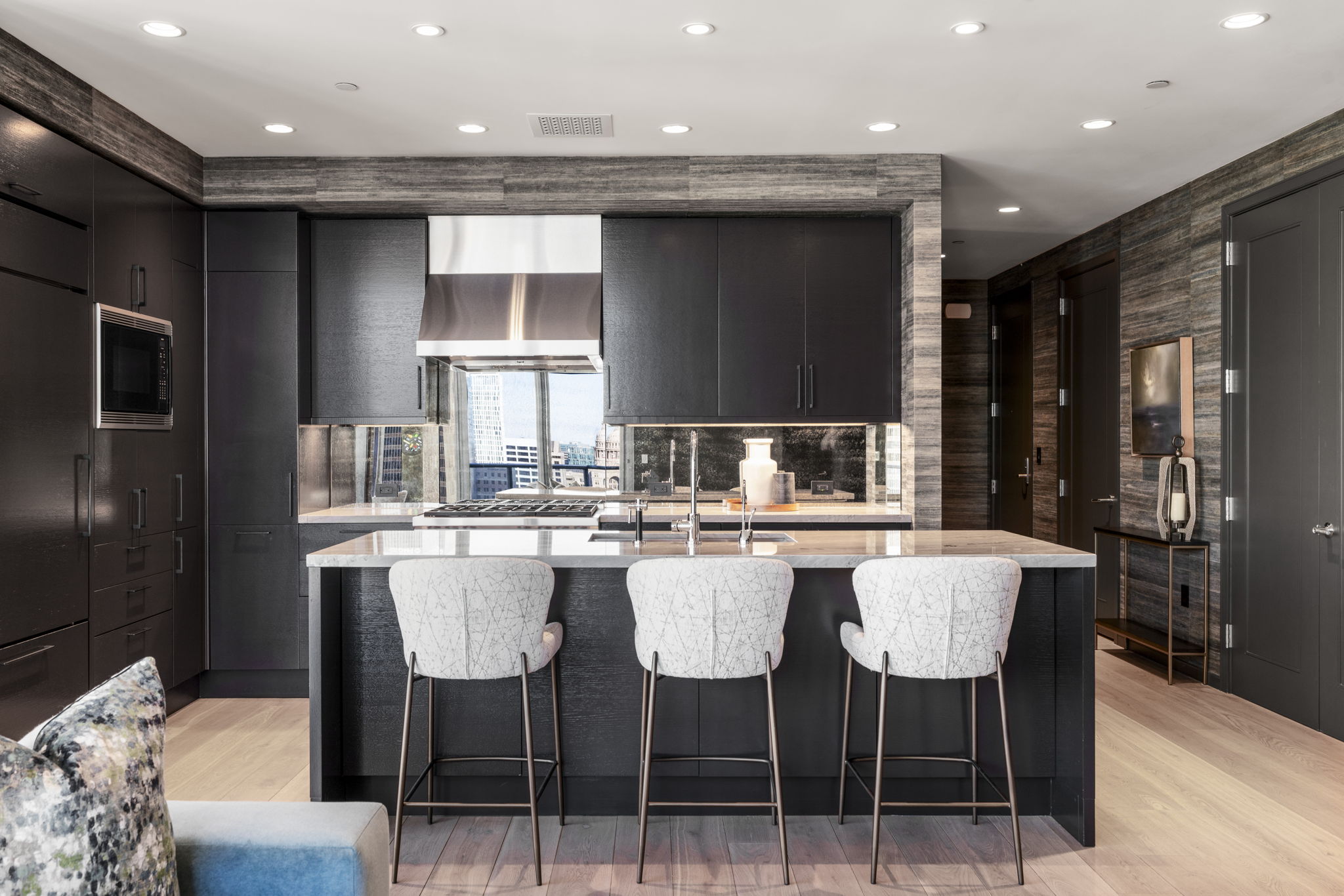 200 Congress Avenue, Unit 21D Austin, TX 78701 - Photo 12 of 34 Kitchen with light stone countertops, a kitchen breakfast bar, dark brown cabinetry, and modern cabinets