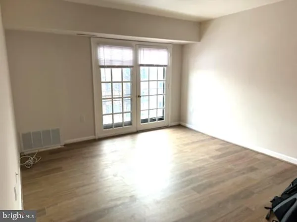 an empty room with wooden floor and windows