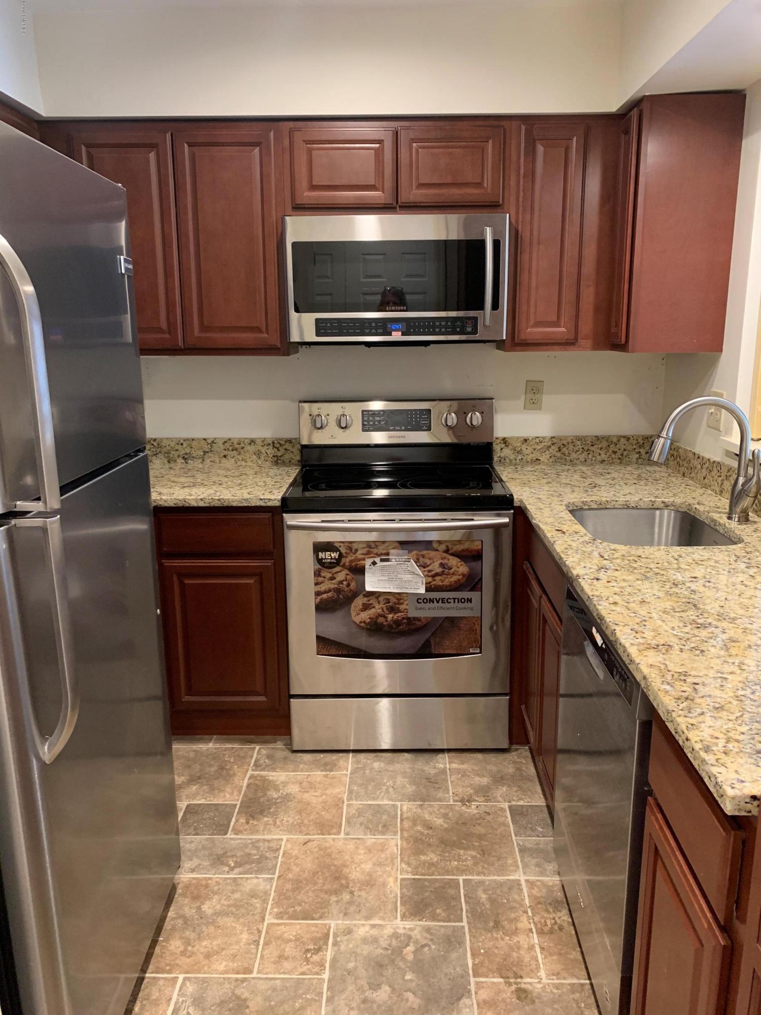 9 River Road, Unit 415 Cos Cob, CT 06807 - Photo 3 of 10 a kitchen with granite countertop a stove top oven microwave and cabinets