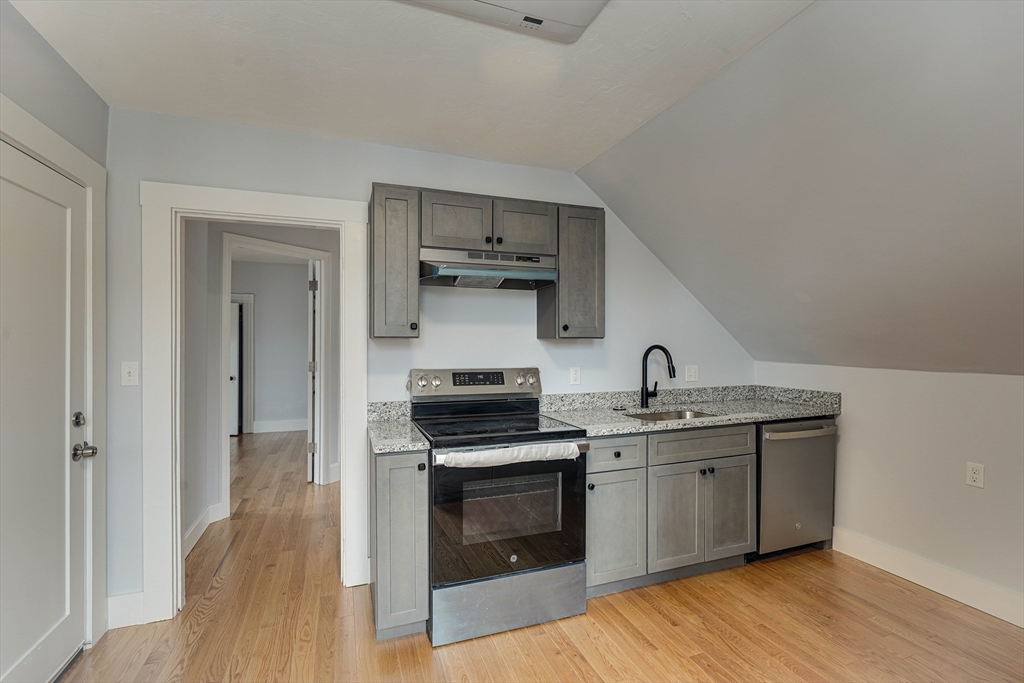 24 Dunlap Street Salem, MA 01970 - Photo 41 of 41 a kitchen with cabinets stainless steel appliances and wooden floor
