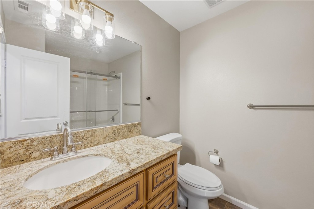956 West Tibbot Street Rialto, CA 92377 - Photo 33 of 37 a bathroom with a granite countertop sink a toilet and a mirror