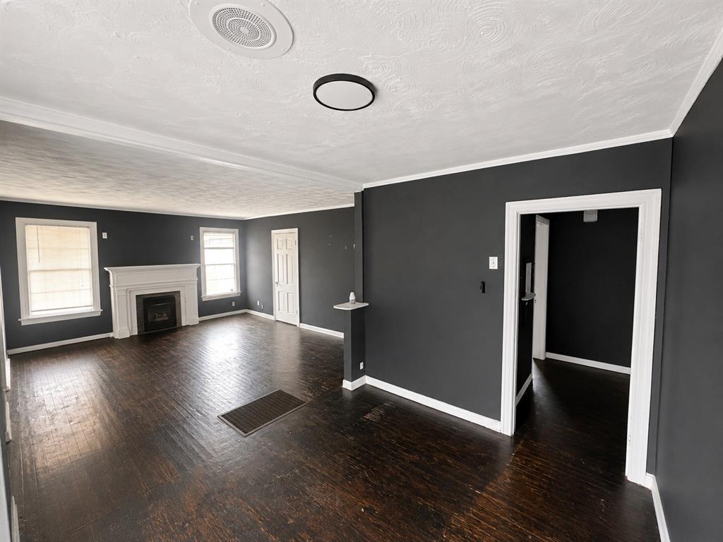 1010 Winters Street Dallas, TX 75216 - Photo 7 of 20 Spacious room featuring dark wood-finish flooring, a white mantel fireplace, and two windows with white trim